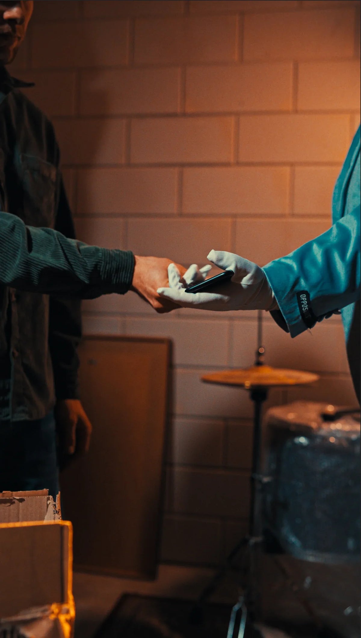 Twee mensen wisselen een smartphone uit in een industriële ruimte, refurbished iPhone