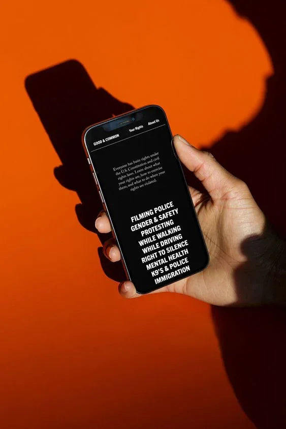 Hand houdt zwarte smartphone tegen fel oranje achtergrond, scherm met witte tekst zichtbaar.