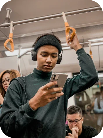 Jongeman gebruikt iPhone in de metro, met koptelefoon en anderen op de achtergrond.